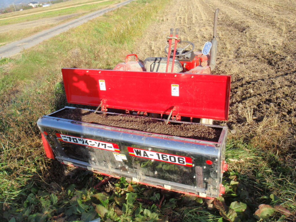 トラクターに取り付けたライムソワー（中にはペレット発酵鶏糞）全体写真