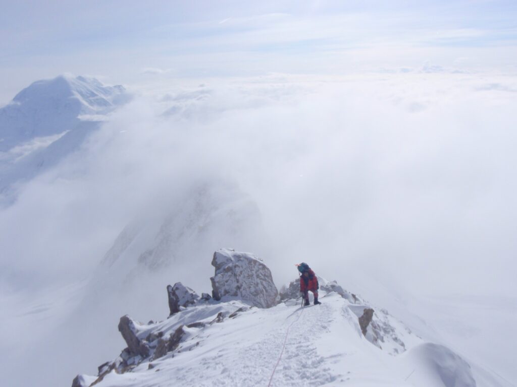 山頂に近づくにつれて難易度が増してくる細い岩稜や雪壁を、足元の状態を慎重に確かめながら登っている小牧久幸